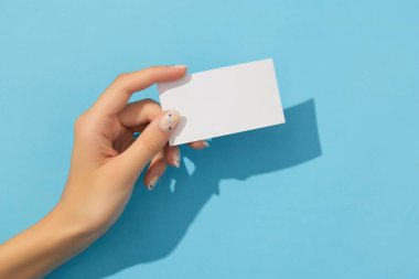 Manikürlü kadınlar mavi arka planda el ele tutuşuyorlar.