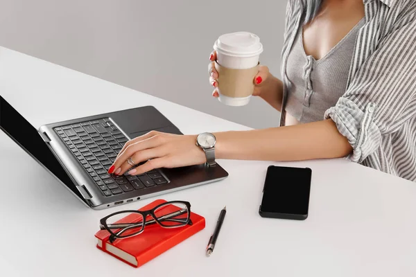 Mujer con trabajo de manicura roja con portátil en mesa blanca. Mujer de negocios trabaja desde casa — Foto de Stock