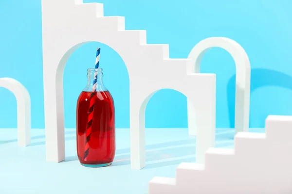 Creative composition with cranberrie lemonade cocktail in bottle on blue background — Stock Photo, Image