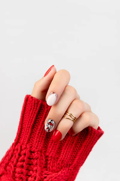 Womans mão em suéter com manicure vermelho no fundo cinza — Fotografia de Stock