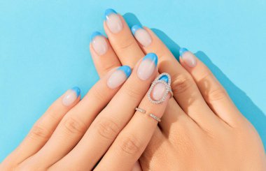 Beautiful womans hands trendy summer nail design on blue background clipart