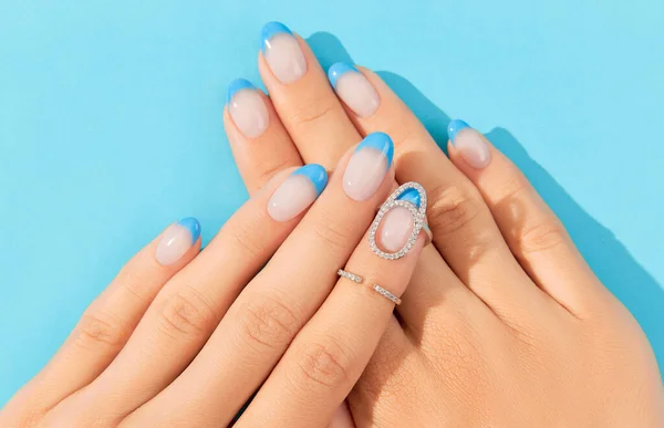Hermosas manos de las mujeres diseño de uñas de verano de moda sobre fondo azul —  Fotos de Stock