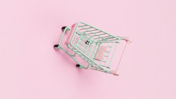 Stop pohyb 4k vertikální video s prázdným zeleným nákupním vozíkem na růžovém pozadí — Stock video