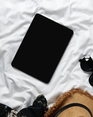 Düz ekran boş ekran dijital tablet giysiler ve aksesuarlar beyaz yatakta yatıyordu. Merkez ofis çalışma alanı.