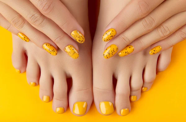 Pernas femininas e mãos com design de unhas de verão no fundo laranja — Fotografia de Stock