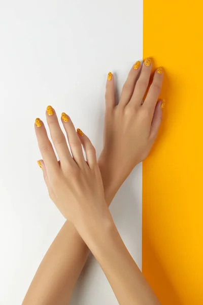 Mujeres cuidadas con diseño de uñas de moda sobre fondo naranja —  Fotos de Stock