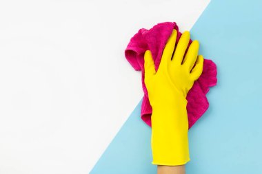 Sarı lastik eldiven giymiş kadınlar mavi arka plandaki paçavraları siliyorlar.