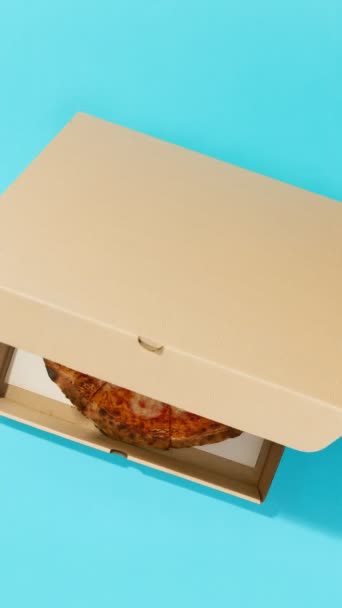 Піца в коробці на синьому столі. Концепція доставки їжі зверху з плоским шаром — стокове відео