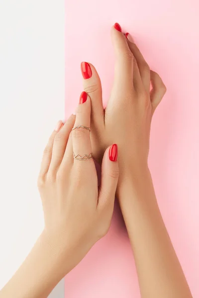 Mani delle donne con manicure rossa alla moda su sfondo bianco e rosa. Trattamento di bellezza spa modello di cura del corpo — Foto Stock