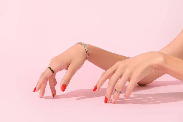 Γυναικεία χέρια με κόκκινο μανικιούρ σε ροζ φόντο. Τάσεις σχεδίασης μανικιούρ — Φωτογραφία Αρχείου