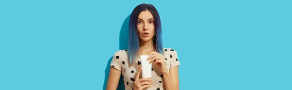 Joven hermosa mujer con cabello azul sosteniendo botella cosmética blanca sobre fondo brillante — Foto de Stock