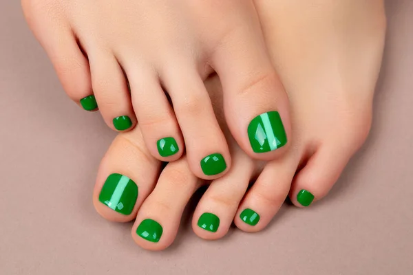 Womans feet with green nail polish on brown background — Fotografia de Stock