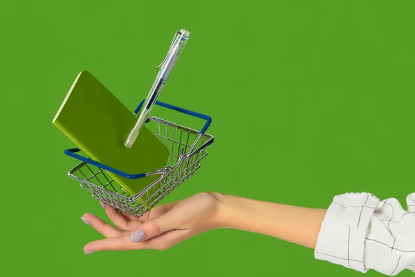 Stationery office supplies with shopping cart levitate on green background — Stock Photo, Image