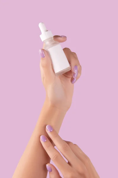 Womans hand holding dropper with serum on pastel lavender background — Stock Photo, Image