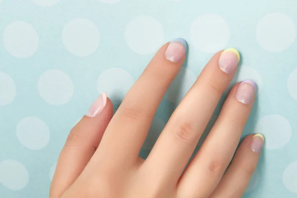 Beautiful womans hand with spring summer nail design on blue background — Stock Photo, Image