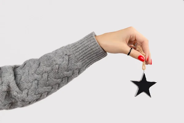 Mano con manicura sosteniendo adornos de estrellas sobre fondo gris con espacio de copia —  Fotos de Stock