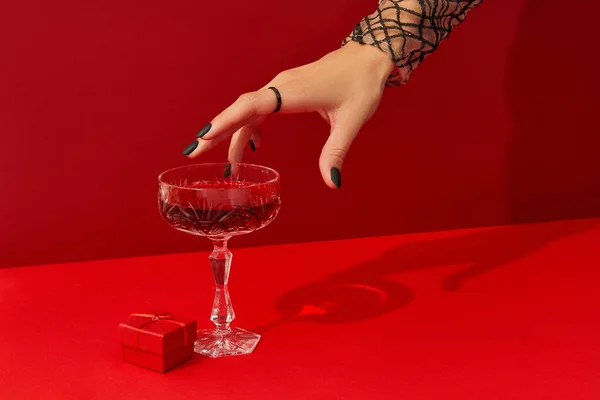 Ženy ruku s strašidelné nehty design vzít sklo s brusinkovou halloween koktejl na červeném pozadí — Stock fotografie