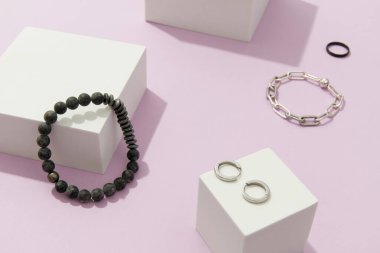 Lavanta arka planında gümüş mücevher olan yaratıcı bir kompozisyon. Minimalist tarzda moda aksesuarlar