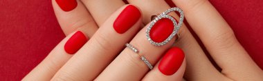 Kırmızı arka planda matt tırnakları olan kadınların ellerini kapat. Manikür, pedikür tasarım eğilimleri
