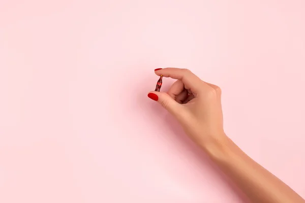 Mão feminina cuidada com pequena garrafa de refrigerante no fundo rosa — Fotografia de Stock