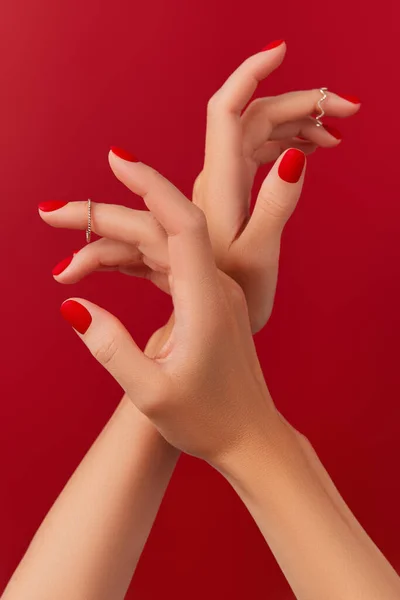 Mãos femininas com manicure na moda em fundo vermelho. Projeto de unhas matt vermelho — Fotografia de Stock