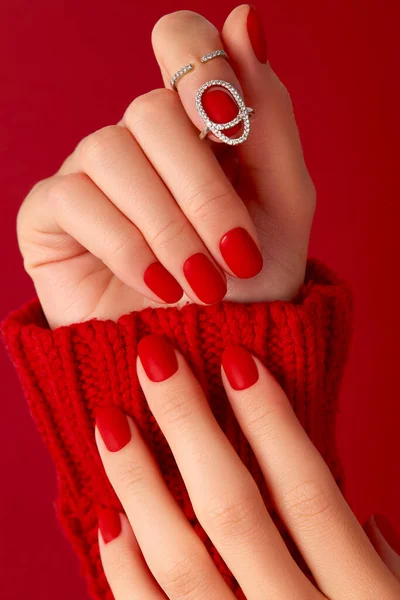 Női kezek manikűrrel pulóverben. Piros matt köröm design — Stock Fotó