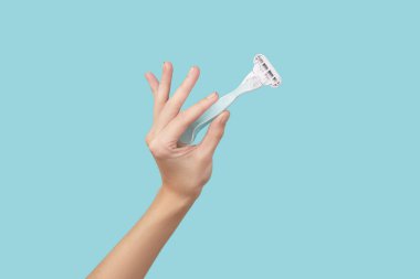 Kesinlik: Bir ustura, çarpıcı bir mavi zemine karşı tutulan, tımar ustalığının özünü yakalıyor. Rutininizi stil ve kontrolle yükseltin