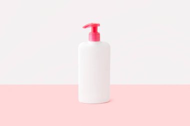 Pastel pembe ve beyaz arka planda bir şişe samimi hijyen jeli. Vücut bakımı güzellik tedavi konsepti. 