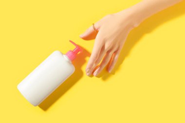 Sarı arka planda beyaz şişeyi tutan kadınlar. Kişisel bakım güzellik tedavi kavramı.