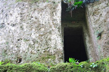 Etrurya mezarlığının detayları. Yeşil arazide ve kayalarda antik mezarlar.