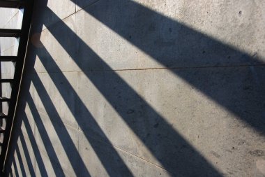 Merdivenlerin gölgesi duvara yansıdı. Belirsiz çizgiler, izole merdiven, güneşli hava..