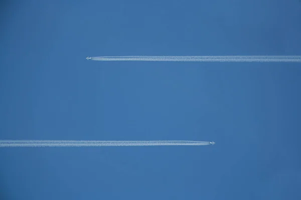 在蓝天上 有两架带着化学痕迹的飞机从相反的方向起飞 — 图库照片