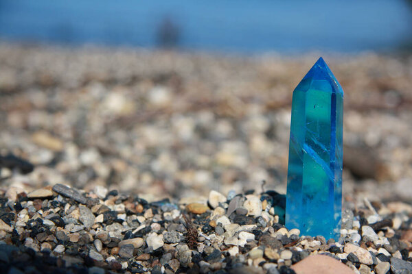 Shiny blue quartz, on the sand of the blurry lake