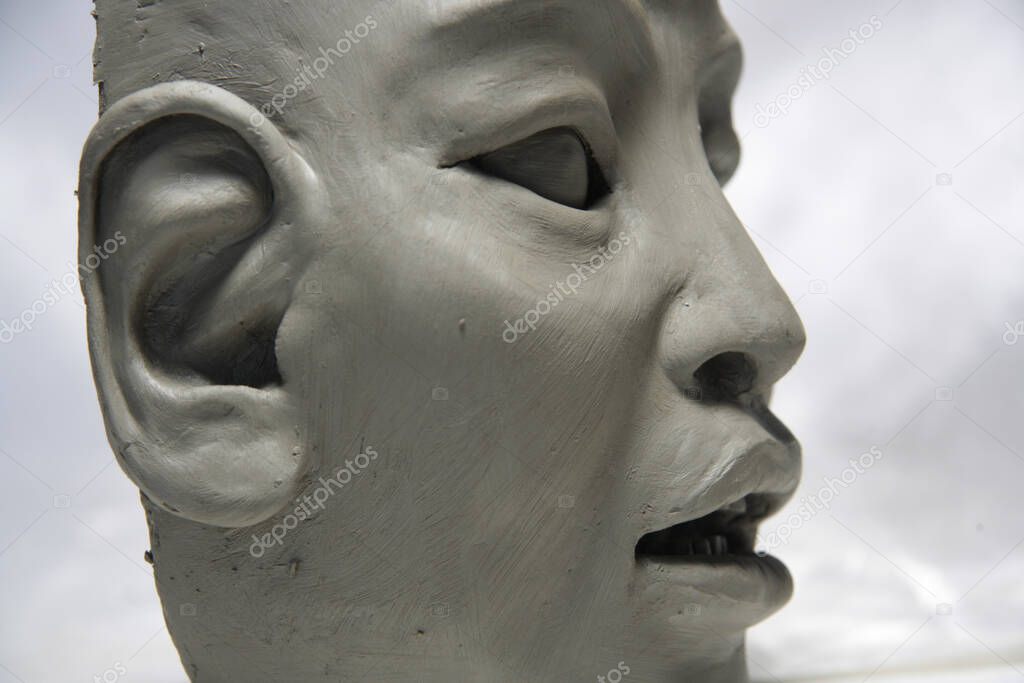 Sculpture of the head, cut. Asian female face, in clay on white background