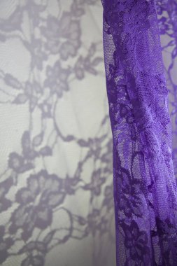 Duvarda, ince dantelin mor perdesinin gölgeleriyle güneş ışığı. Zarif doku, mahsul, çiçek deseni ve beyaz soyut alan. Metin için alanı olan dikey resim.