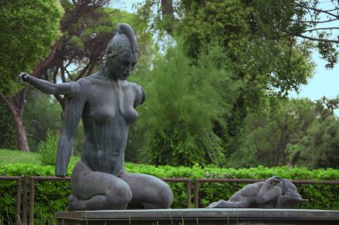 Uzaylı özellikleri olan yerli bir kadın heykeli ve yerde yatan bacaksız bir çocuk. Roma 'nın Eur bölgesinde, doğadaki büyük metal heykel..