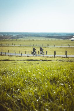 Elderly couple cycling up the VAM-Berg in Drenthe, The Netherlands. The VAM-Berg is an artificial hill created for leisure purposes. This was a sunny day in 2020. clipart