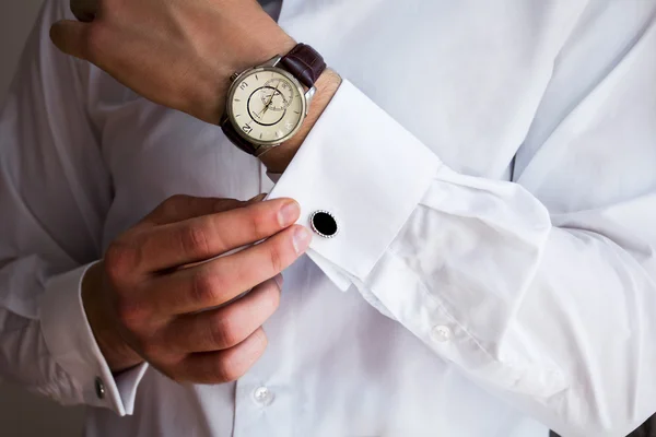 Férfi kéz a háttérben egy fehér ing, ingujj mandzsettagombokkal és órákkal, fényképezett közelkép — Stock Fotó