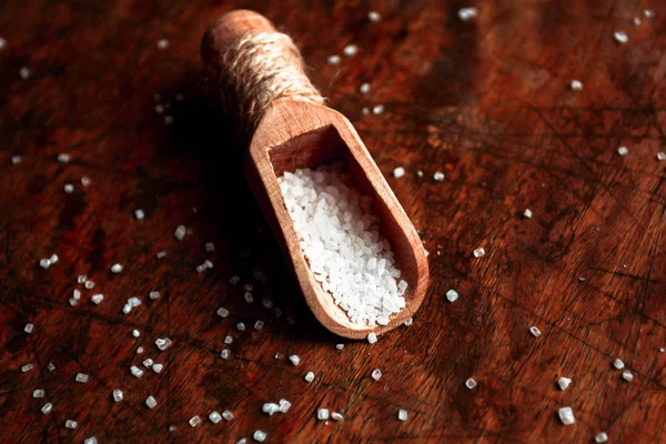 Açúcar em uma colher de madeira em um fundo rústico velho escuro — Fotografia de Stock