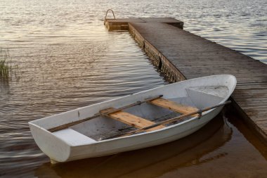 Rıhtımın yanındaki gölde yüzen küçük beyaz tekne.