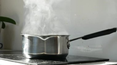 Mutfaktaki elektrikli ocağın üstünde buharla kaynar su.