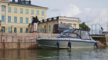 Küçük tekne güneşli bir günde Helsinki rıhtımına yanaştı. Arka planda arabalar, bisikletler ve scooterlar olan Helsinki City.