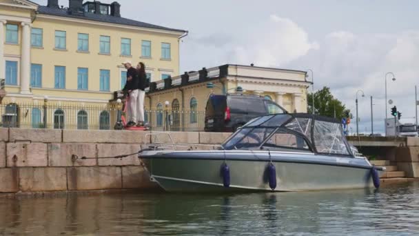 在平静的晴天 小船停泊在赫尔辛基的码头上 赫尔辛基市 后面有汽车 自行车和摩托车驾驶 — 图库视频影像