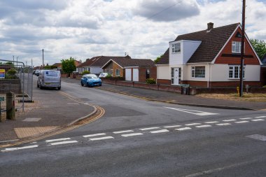 Norwich, UK- 17 Mayıs 2025: Tipik bir İngiliz banliyö sokağı, bungalovları ve Norwich 'te evleri var. Bulutlu bir günde park halindeki arabaların ve bulutlu bir gökyüzünün bulunduğu yerleşim yeri..