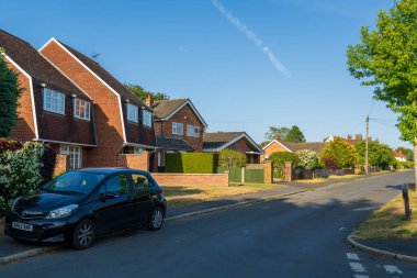 Norwich, UK- 17 Mayıs 2025 Norwich, Norfolk 'ta tuğla evleri ve çitleri olan huzurlu bir mahalle sokağı. Tipik İngiliz banliyösü emlak sahnesi