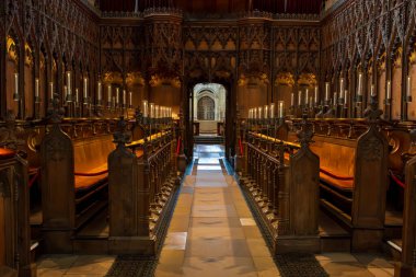 Norwich, UK- 17 Mayıs 2025: Norwich, İngiltere 'de karmaşık Gotik ahşap işleri ve oyma tepe örtüleri olan ortaçağ katedrali korosu. Ilık aydınlatma dekoratif detayları aydınlatır