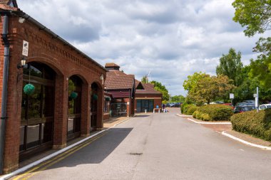 Norwich, UK- 17 Mayıs 2025: Viktorya dönemi kemerleri ve Norwich, İngiltere 'de manzaralı bahçeleri, çitleri ve dramatik yaz bulut oluşumunun yer aldığı geleneksel tuğla otel dış görünüşü