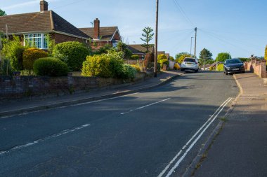 Norwich, UK- 17 Mayıs 2025 Norwich 'in kenar mahallelerinde tuğla evleri ve bahçeleri olan sakin bir yerleşim yeri. Park etmiş arabaları ve yeşil peyzajı olan tipik İngiliz mahallesi yolu..