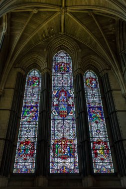 Norwich, UK- 17 Mayıs 2025: Gotik bir kilisede tırtıklı kubbeli bir ortaçağ vitray penceresi. Renkli kurşunlu camla İncil 'e ait sahnelerin yer aldığı dekoratif bir katedral..