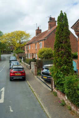 Cromer, UK- 18 Mayıs 2025: Tarihi Tuğla Kulübeleri ve Park Aracı, Lush Green Gardens Sahnesi ile Geleneksel Residential Area